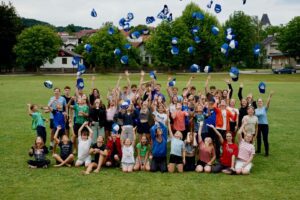 mFg Lagerwoche 2025, Kinder und Betreuer werfen deren Kappen in die Luft.